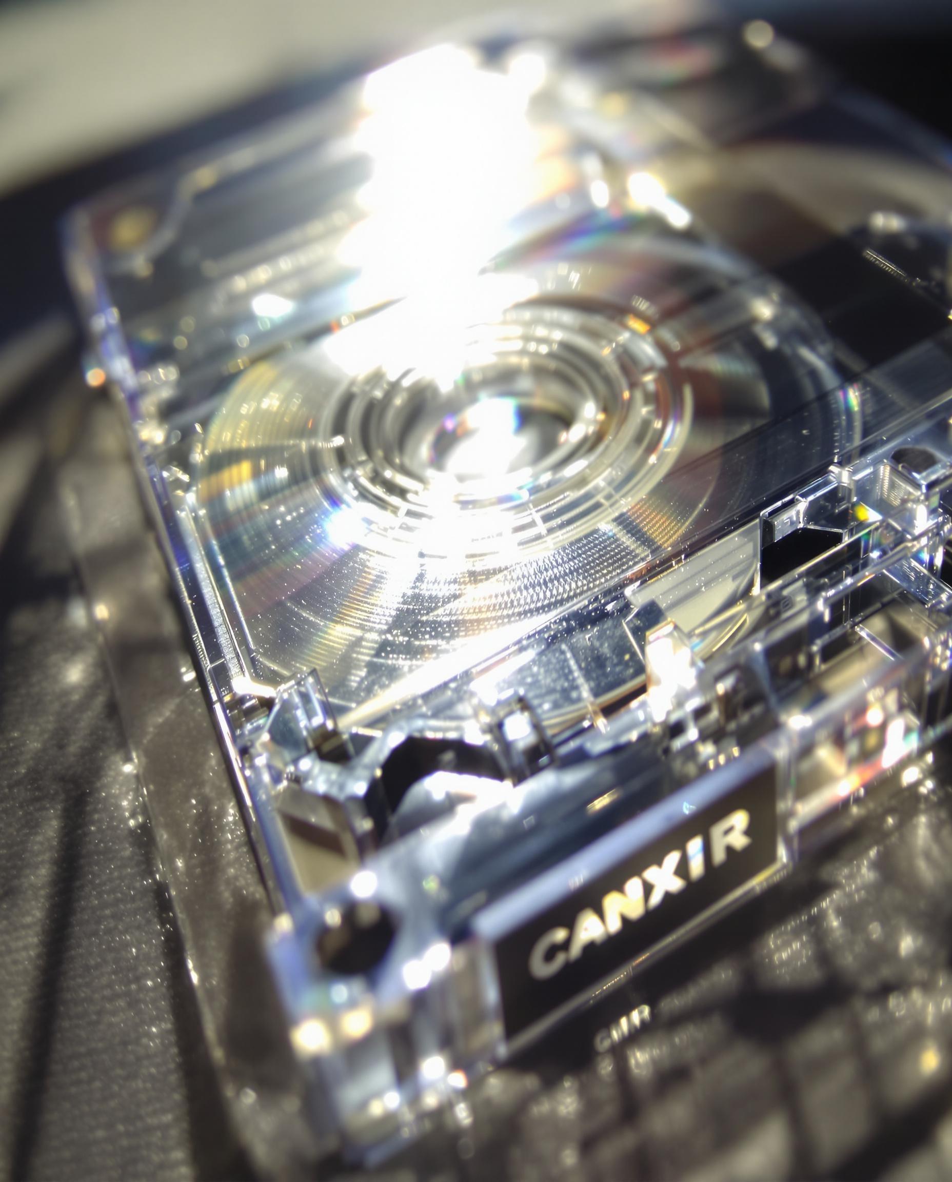 Cassette audio transparente, bande magnétique luisant sous la lumière.