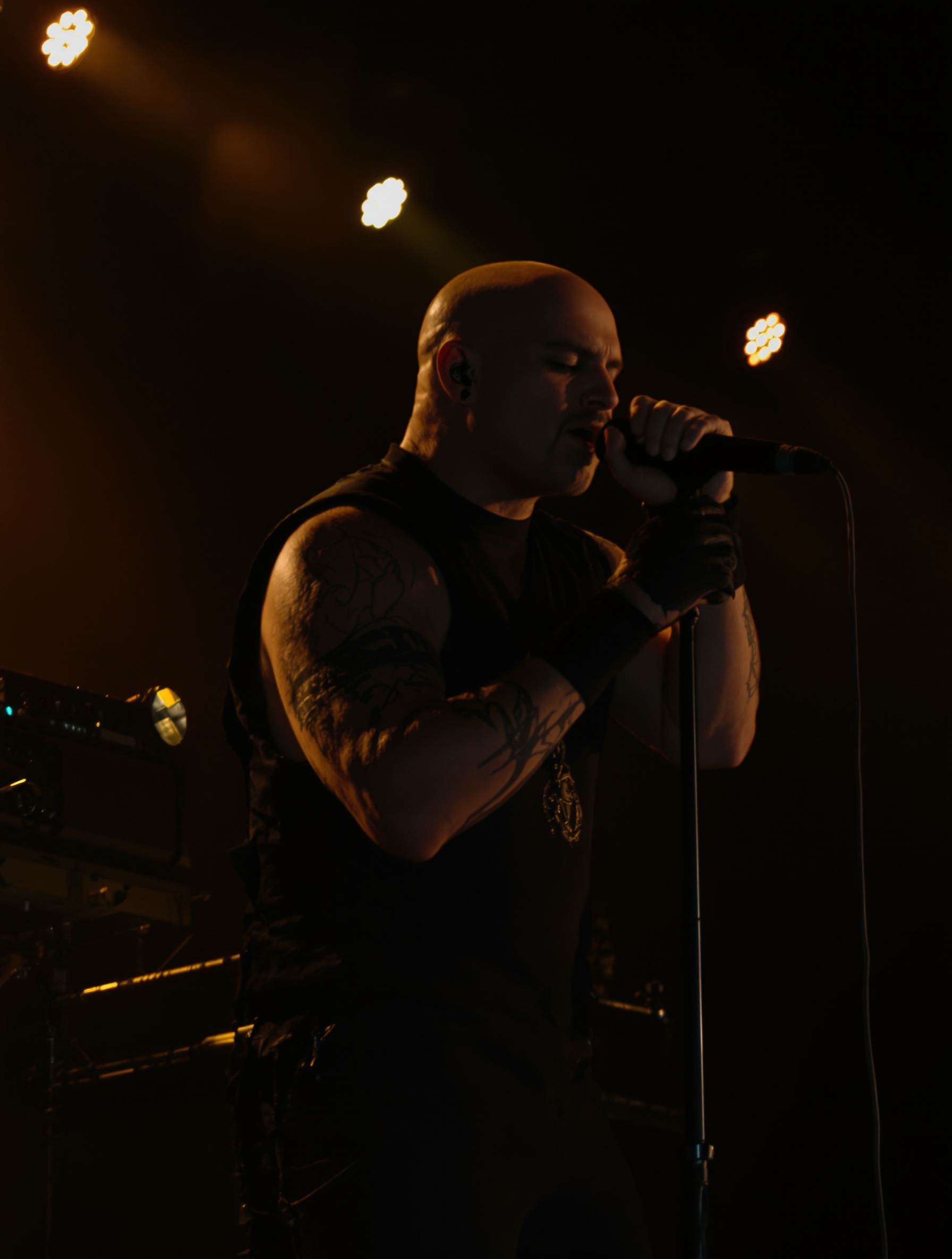 David Draiman en pleine performance vocale sur 'The Sound of Silence', la lumière sculpte ses traits, fusion entre puissance et fragilité.