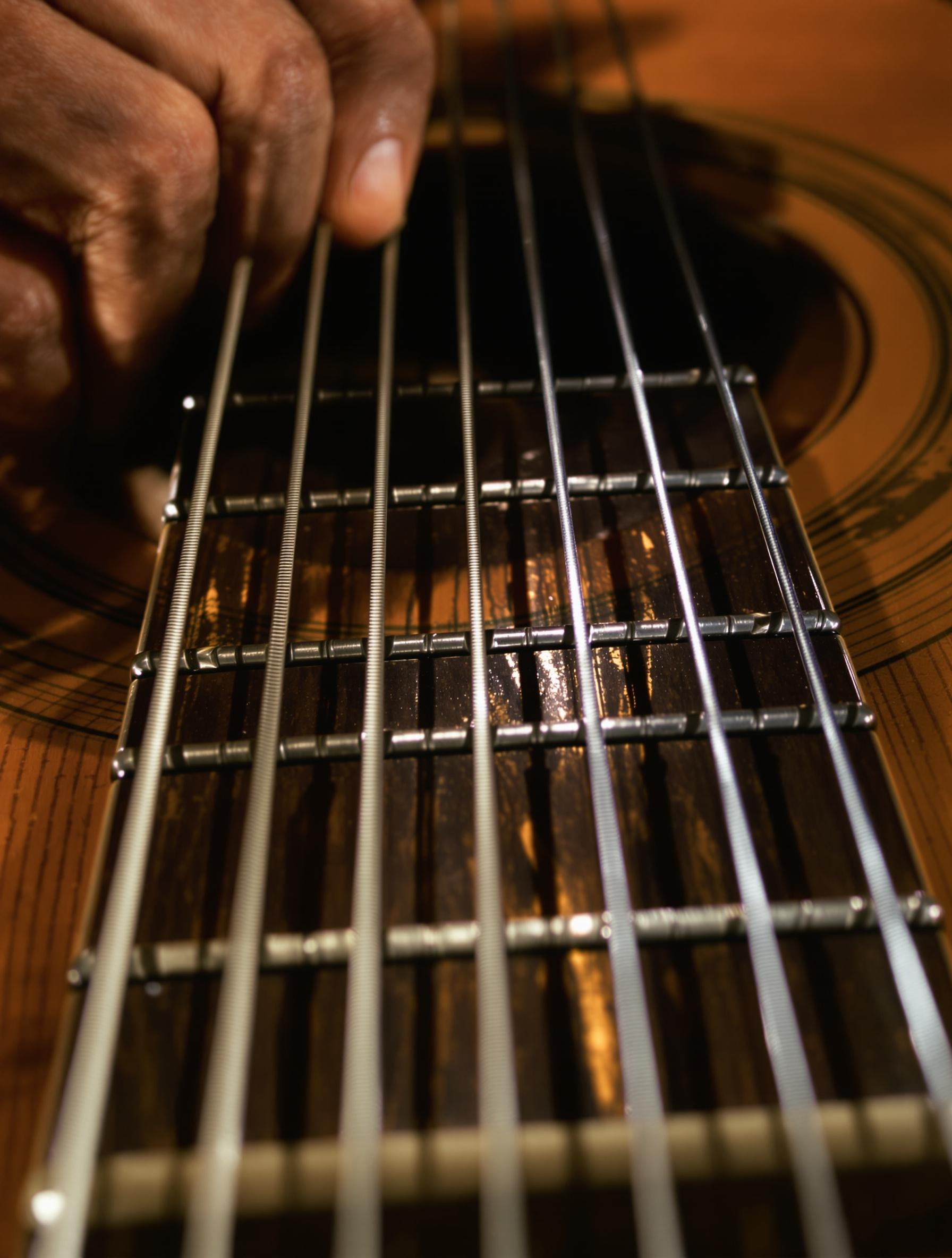 Gros plan sur la guitare de Paco de Lucía – main droite en pleine alzapúa, cordes tendues sous une lumière chaude