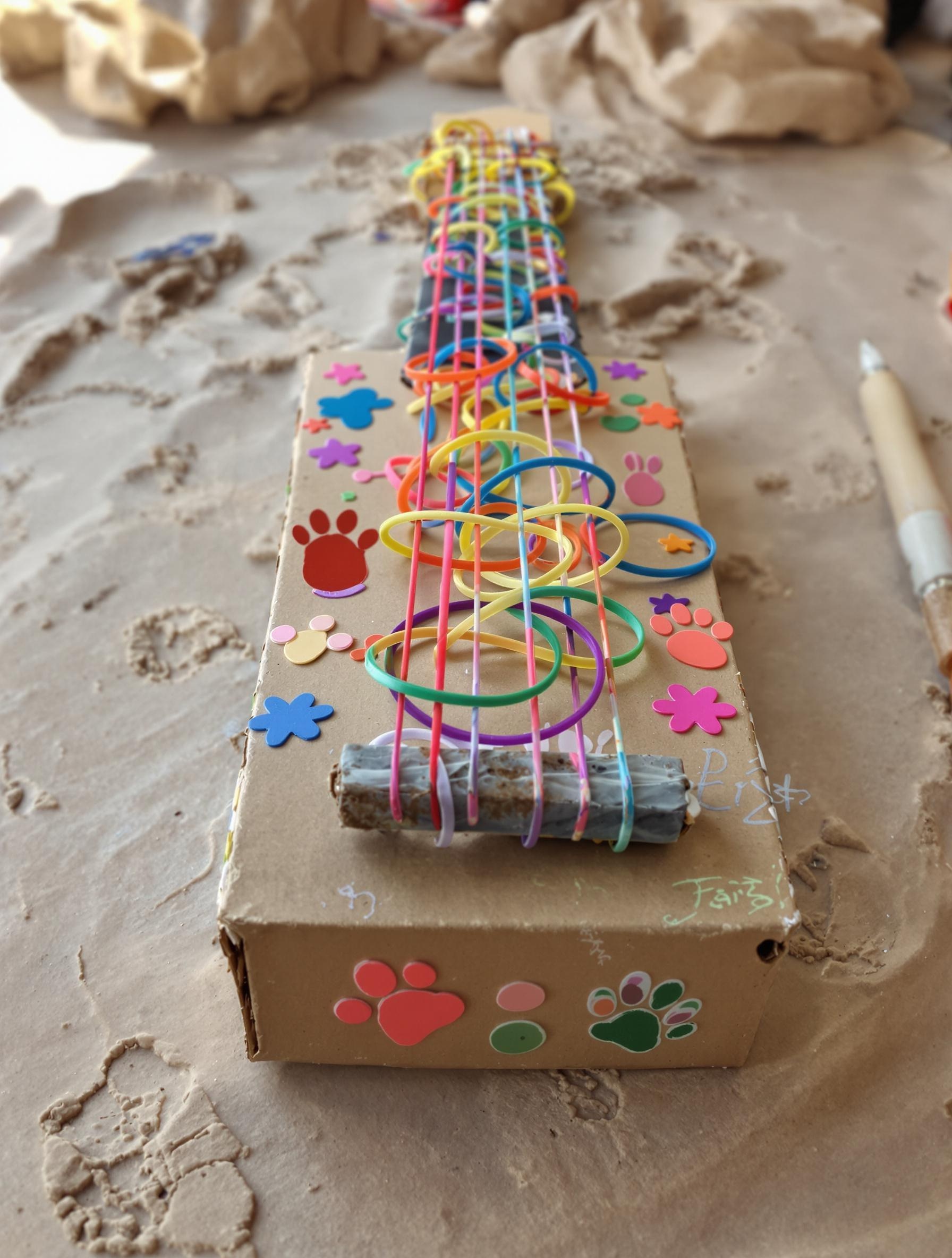 Guitare fabriquée à partir d’une boîte à mouchoirs et d’élastiques colorés.