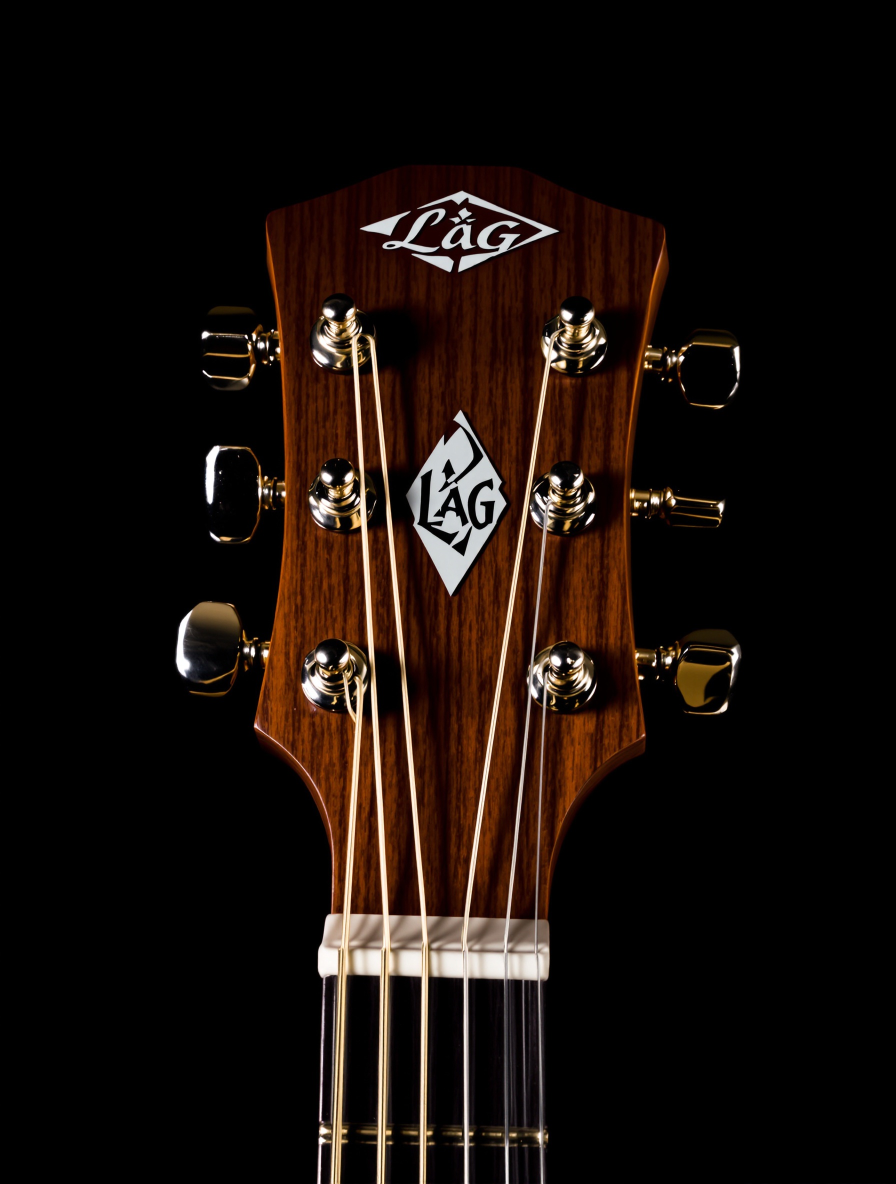 Gros plan sur la tête distinctive d'une guitare Lâg, logo bien visible sur fond sombre