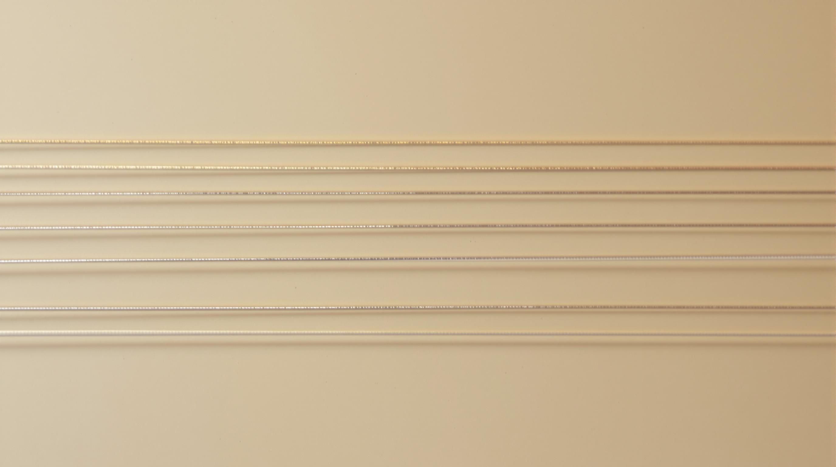 Photographie artistique de trois jeux de cordes de guitare classique, illustrant visuellement les différences entre tension légère, normale et forte