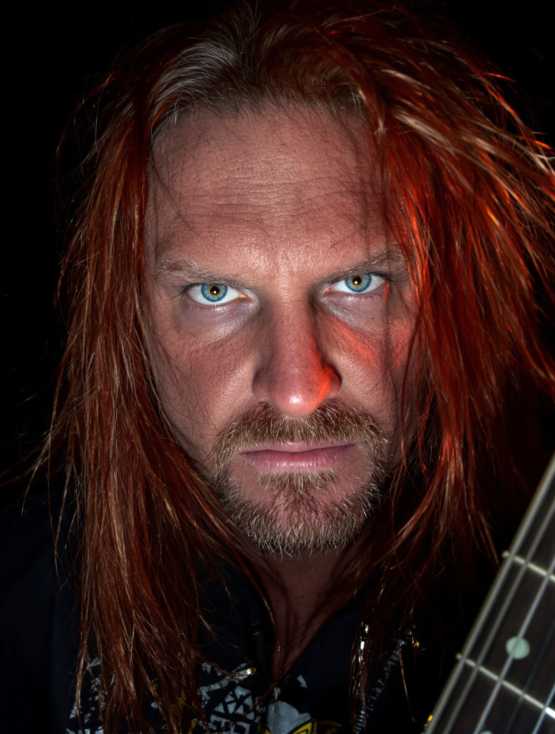 Portrait de Dave Mustaine, le regard intense, guitare à la main.